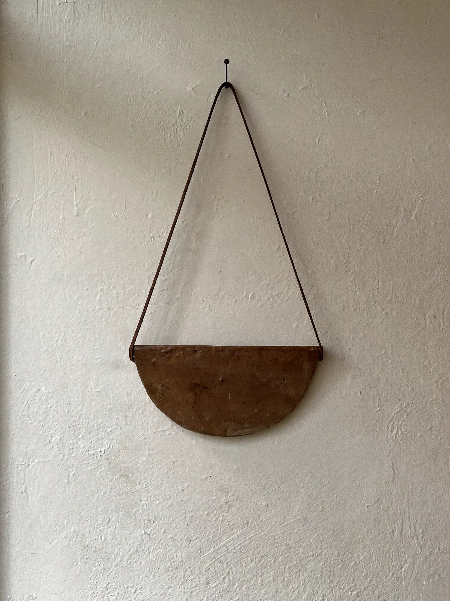 Hanging Cup stoneware planter in raw clay glaze, on a stone block against a plaster wall